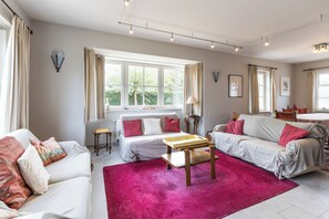 Ein geräumiges Wohnzimmer mit großem Fenster, einer Sofagarnitur, einem Couchtisch und einem Essbereich.