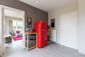 A compact kitchen with a red refrigerator, a wooden table with a metal rack, and a white door. - 4 bedroom accommodation in Sint Idesbald (Sint Idesbald)