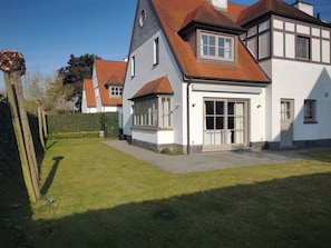 A residential property with a well-maintained lawn, a driveway, and a house featuring a gabled roof and large windows. - 4 bedroom accommodation in Sint Idesbald (Sint Idesbald)