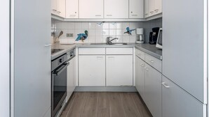 A compact kitchen with white cabinets, a built-in oven, a sink, and a coffee maker. - 2 bedroom accommodation in Sint-Idesbald (Sint-Idesbald)