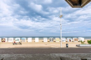 A beach with a row of white planters, a bench, and a bicycle. - 2 bedroom accommodation in Sint-Idesbald (Sint-Idesbald)