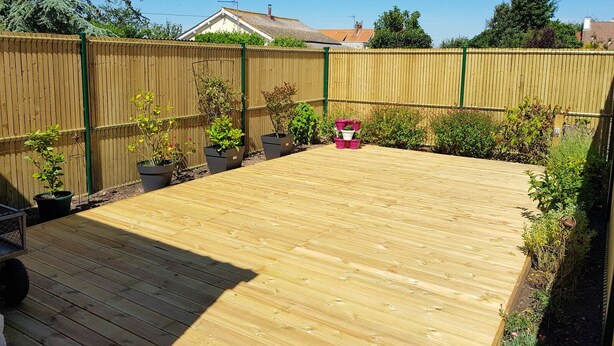Una terraza de madera con macetas y una pequeña mesa.