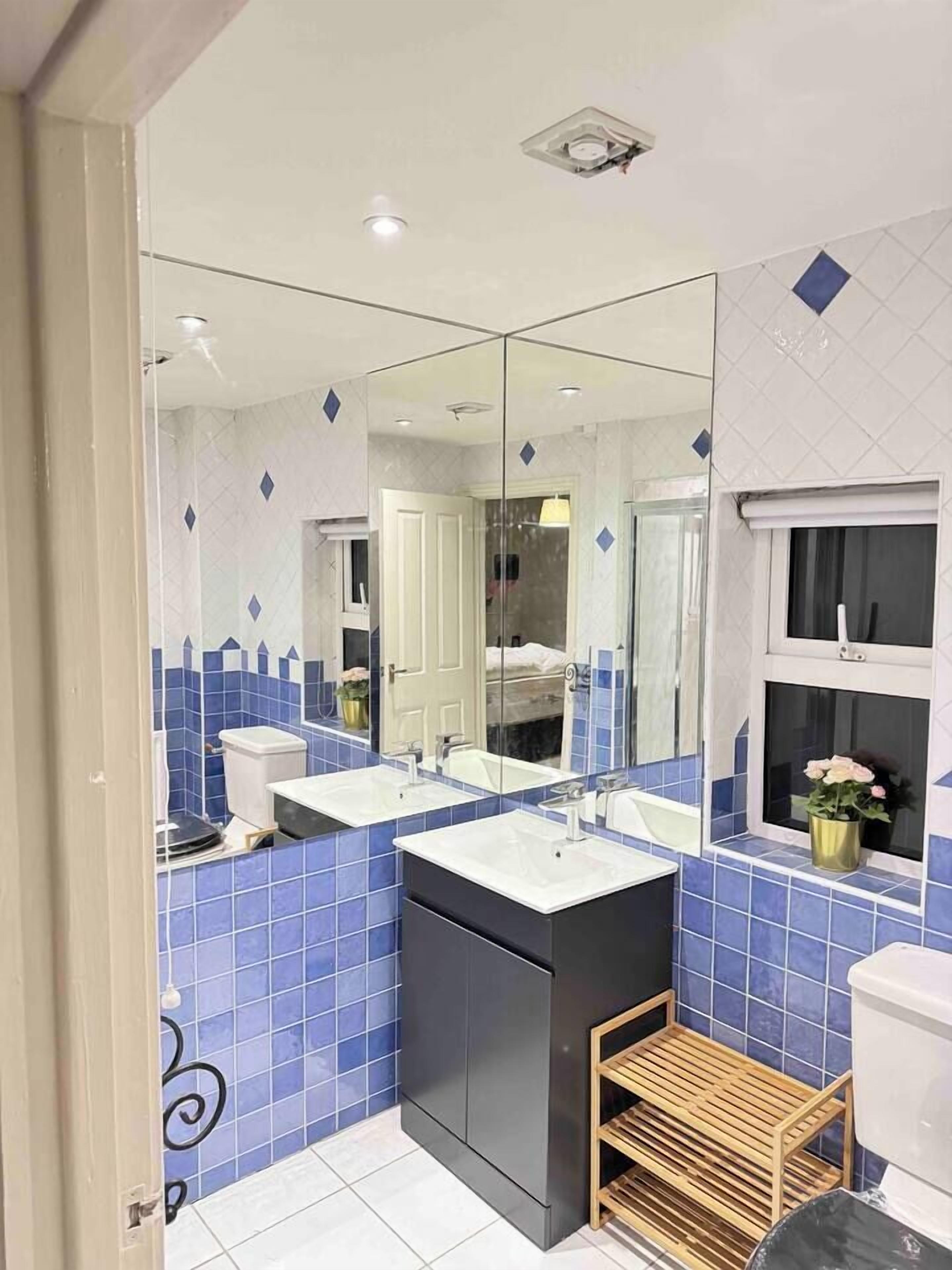 Un baño moderno con dos lavamanos, un espejo grande y una ventana.