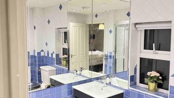 Un baño moderno con dos lavamanos, un espejo grande y una ventana.
