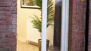 Fachada de ladrillo con puerta de cristal que da acceso a un espacio interior.