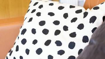 A close-up of a polka-dotted pillow on a brown leather couch.