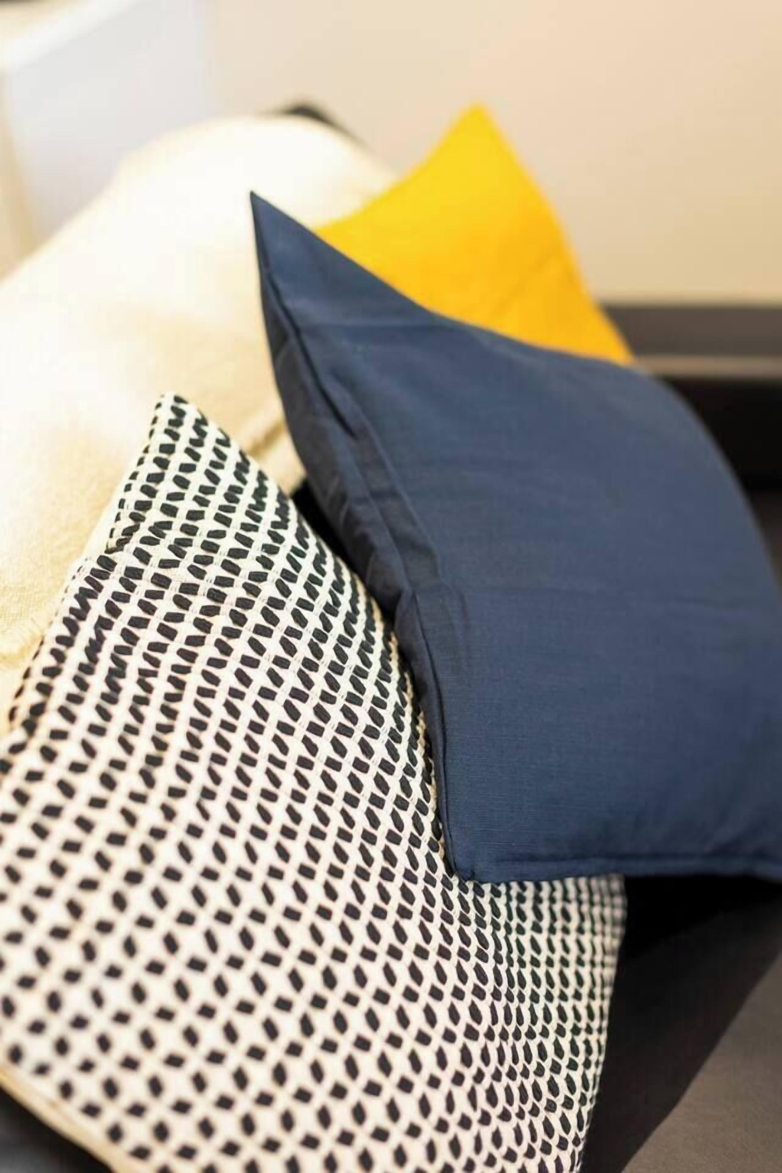 A bed with patterned pillows and a plain pillow.
