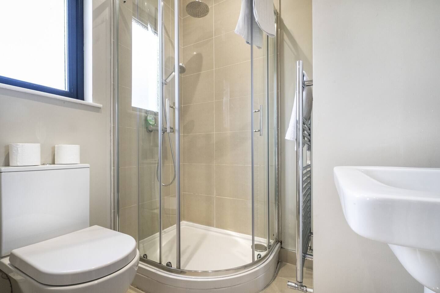 Une salle de bain moderne dotée d’une douche à parois de verre, de toilettes et d’un lavabo.