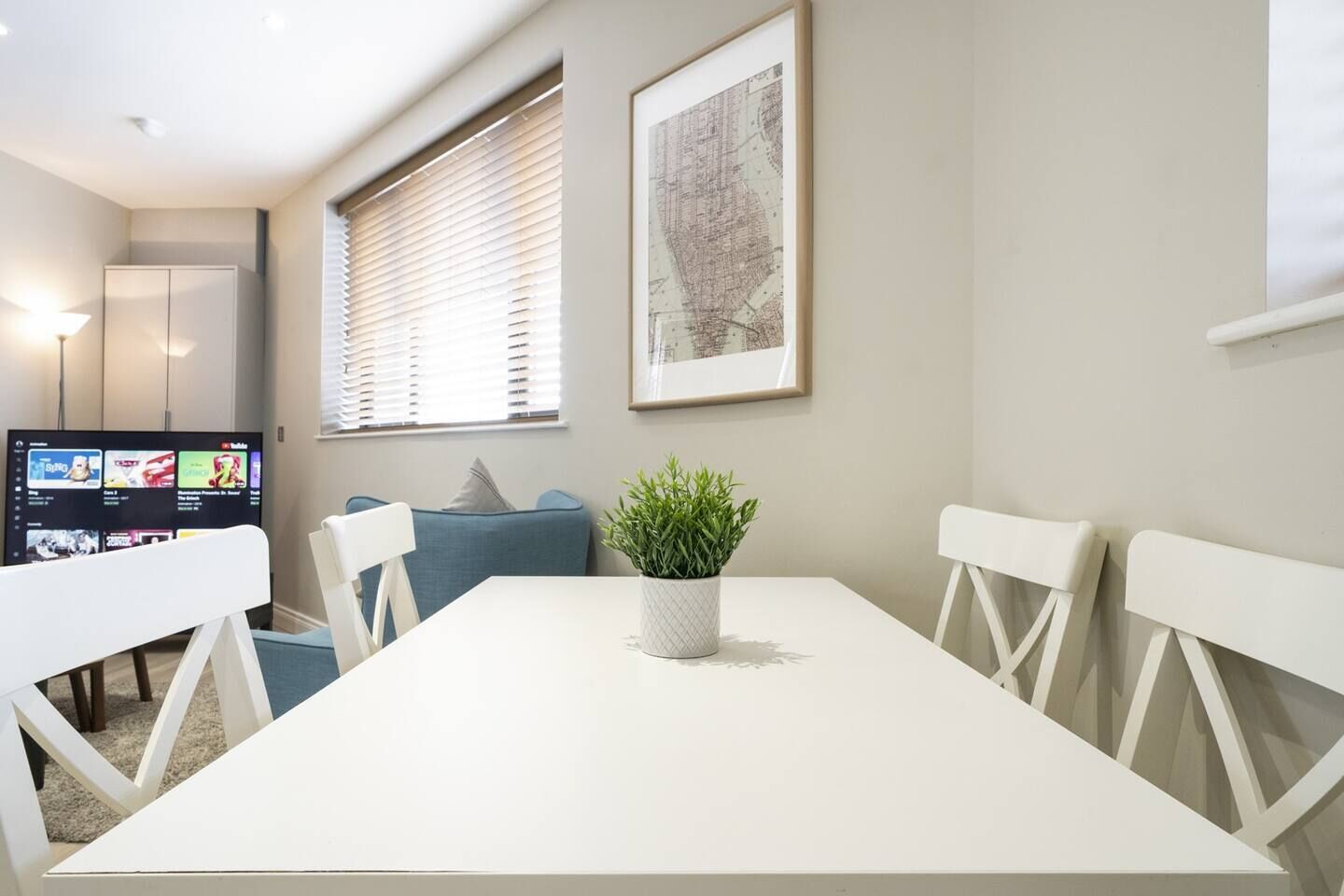 Une pièce moderne avec une table blanche, un canapé bleu et une plante en pot.