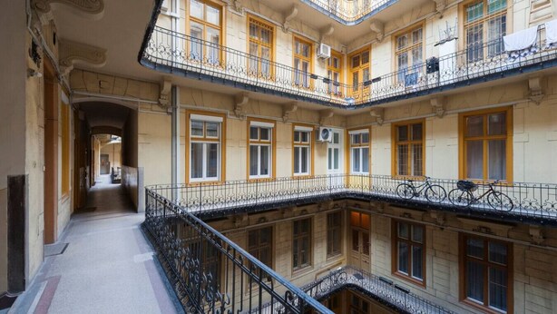 Ein mehrstöckiges Gebäude mit Balkonen, einem Innenhof und einer Treppe, die zu den oberen Stockwerken führt.