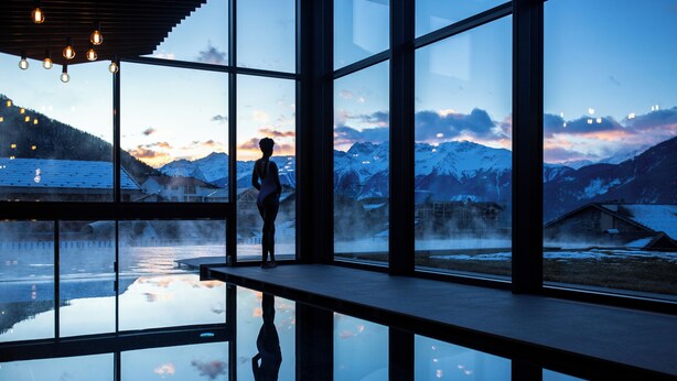 A modern interior with large windows offering a view of a snowy mountain landscape.