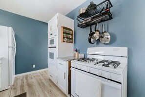 Une cuisine avec des appareils électroménagers blancs, un mur bleu et un porte-ustensiles.