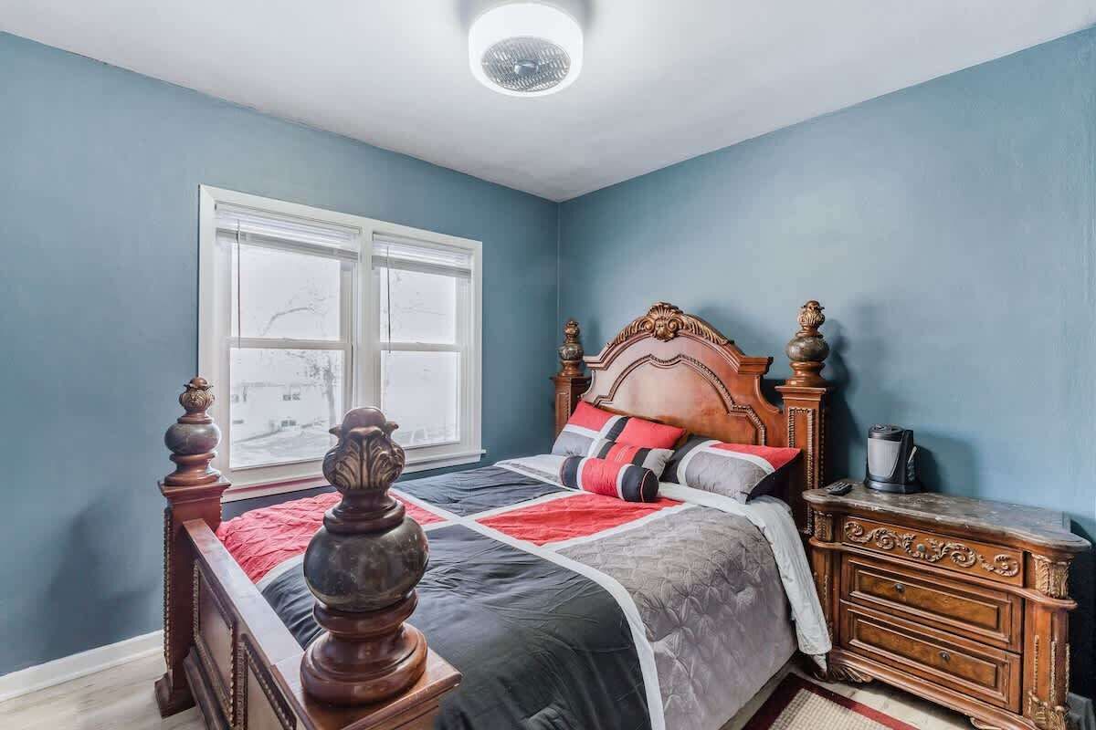 Une chambre à coucher avec un grand lit, une commode, une fenêtre et un luminaire au plafond.