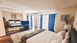 A bedroom with a large bed, a desk with a chair, a television, and a window with curtains. - Cozy 3-Bedroom Condo by the Lake & Skiing (Incline Village)