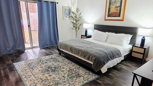 A bedroom with a bed, two bedside tables, a nightstand, a large rug, a window with curtains, and a wall-mounted picture. - Cozy 3-Bedroom Condo by the Lake & Skiing (Incline Village)