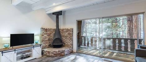 A modern living room with a fireplace, a television, and a sliding glass door leading to a balcony.
