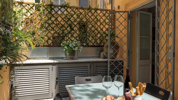 An outdoor dining area with a table set for two, featuring a bottle of wine, glasses, breadsticks, olives, and fruits. - Terrace Downtown Appartment (Roma)