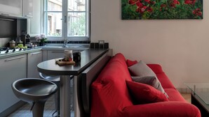 A modern kitchen with a dining area, a red sofa, and a painting of red flowers on the wall. - Terrace Downtown Appartment (Roma)
