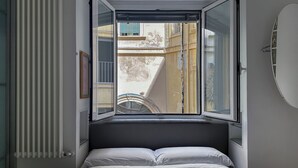 A bedroom with a bed, a radiator, and a window with an open shutter. - Terrace Downtown Appartment (Roma)