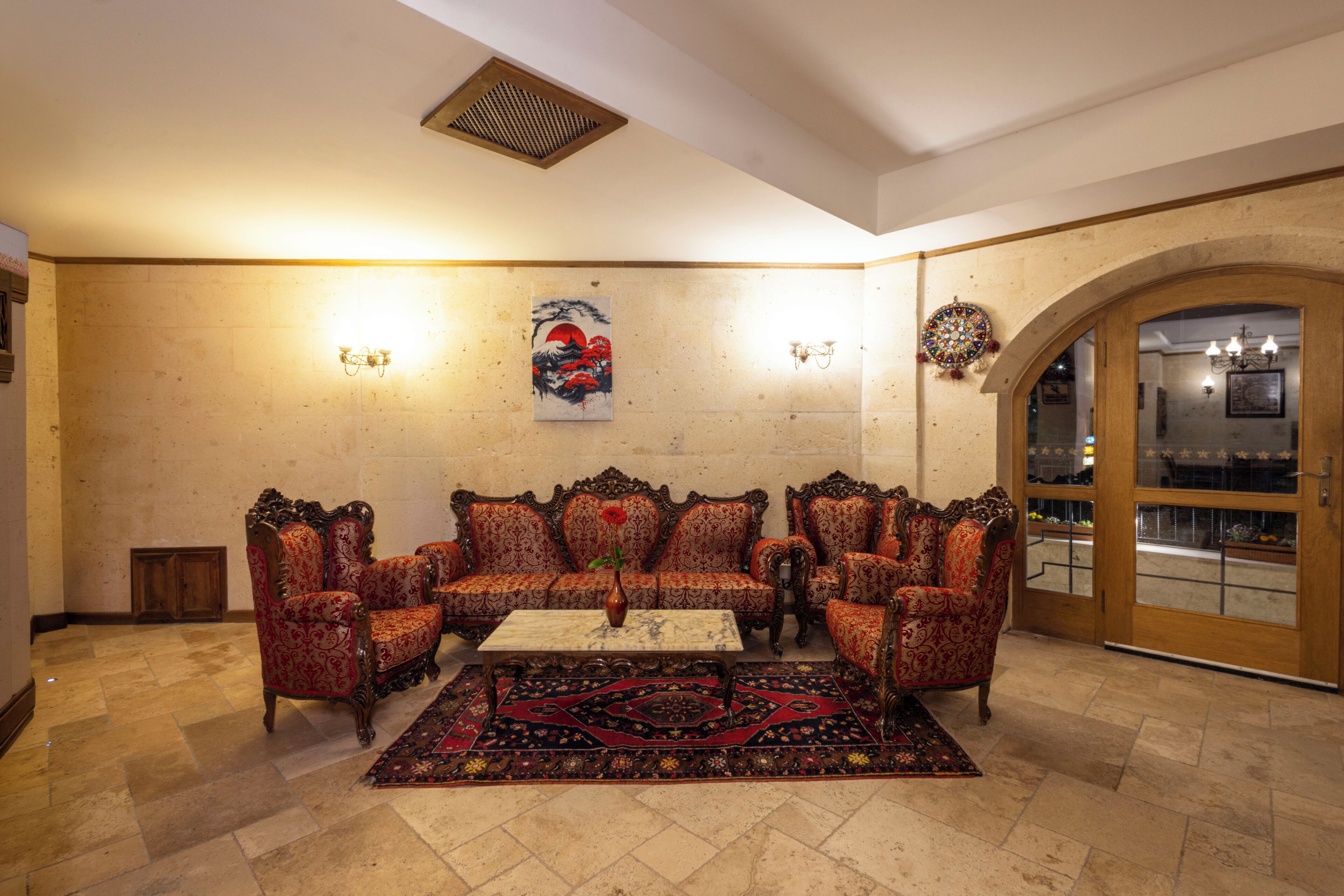A traditional living room with ornate furniture, a patterned rug, and a wall-mounted artwork.