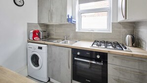 A compact kitchen with a washing machine, dishwasher, gas stove, and a window providing natural light. - Host Stay Shaftsbury (Nottingham)