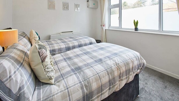 A bedroom with a bed, a radiator, a window with curtains, and a small plant on the windowsill. - Host Stay Shaftsbury (Nottingham)