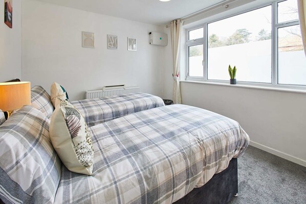 A bedroom with a bed, a radiator, a window with curtains, and a small plant on the windowsill. - Host Stay Shaftsbury (Nottingham)