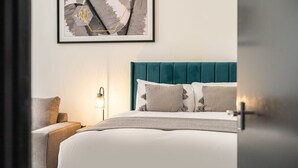 A bedroom with a teal upholstered headboard, a white bedspread, and a bedside lamp. - Host Stay Exchange Street Living (Liverpool)