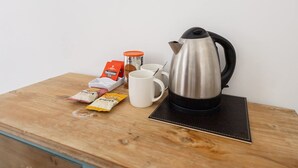A wooden table with a stainless steel kettle, a white mug, a small orange container, and packets of tea and coffee. - Host Stay Goathland at the Sandbeck (Whitby)