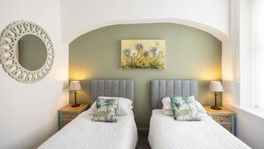 A bedroom with two beds, a decorative mirror, and a painting on the wall. - Host Stay Goathland at the Sandbeck (Whitby)