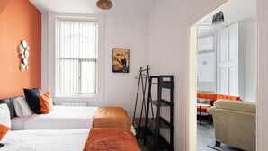 A hotel room with two beds, a large window, a painting, and a view of the outdoor seating area.