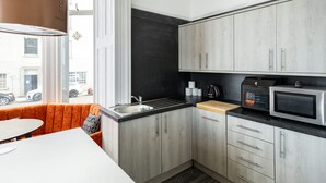 A modern kitchen with grey cabinets, a black backsplash, and a wooden countertop.