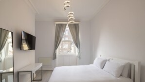 A modern bedroom with a large bed, a bedside table, a TV mounted on the wall, and a window with curtains. - Host Stay Aberdeen Walk Apartment (Scarborough)