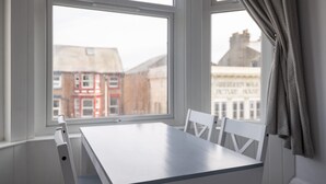 A room with a white table and chairs, large windows with a view of buildings, and a curtain on the right side. - Host Stay Aberdeen Walk Apartment (Scarborough)