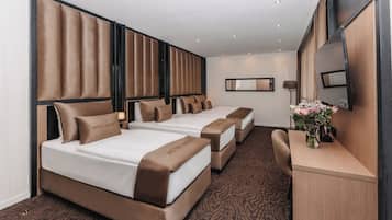 A hotel room with three beds, a desk, and a mirror.