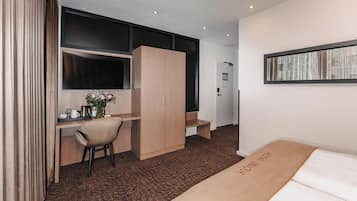 Ein Hotelzimmer mit Bett, Schreibtisch, Stuhl, Kleiderschrank, Fernseher und Fenster.