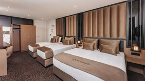 A hotel room with two beds, a desk, and a wardrobe. - Hotel Unique Majestic Hauptbahnhof (Dortmund)
