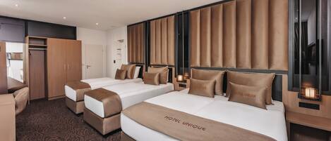 A hotel room with two beds, a desk, and a wardrobe.