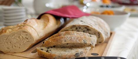 A wooden cutting board with sliced bread and a knife.