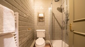 A bathroom with a toilet, a glass shower enclosure, and a towel rack.