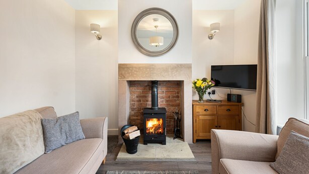 A cozy living room with a fireplace, sofas, a television, and a mirror on the wall.