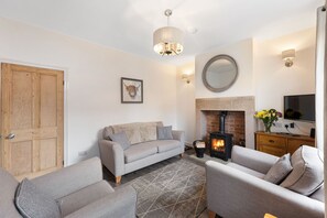 Una sala de estar acogedora con un sofá, sillones, chimenea y televisor.
