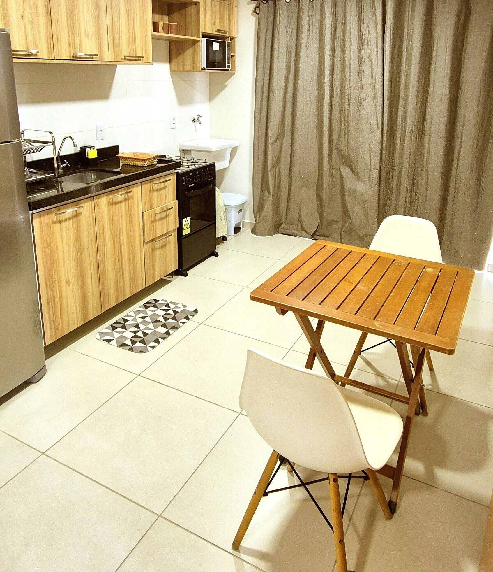 A compact kitchen with wooden cabinets, a black stove, and a dining table with chairs.
