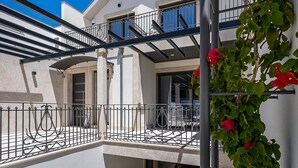 A two-story building with a balcony, a metal railing, and a clear blue sky.