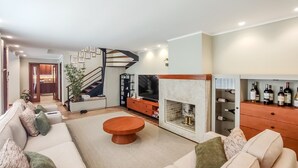 Ein modernes Wohnzimmer mit Sofa, Couchtisch, Kamin und Weinkühlschrank.