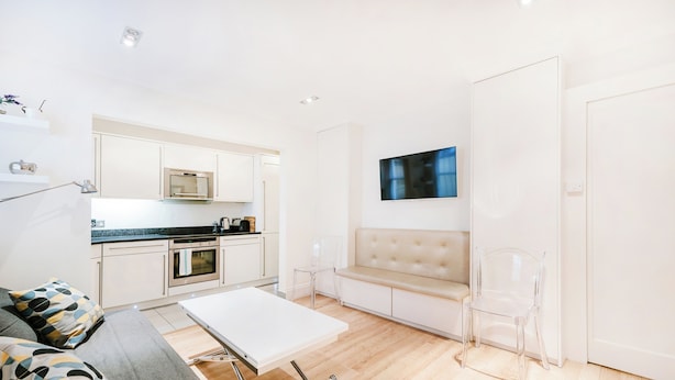 A modern kitchen with white cabinets, a microwave, and a dining area with a table and chairs. - Xxxxxxxxxxxxxxxxxxxxxxxxxxxxxxxxxxxx (London)