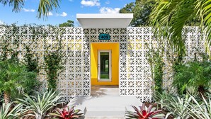 A building with a white lattice facade, a yellow door, and a blue sign with the number 409. - Palm Springer - Heated Salt Water Pool Steps from the Drive (Wilton Manors)