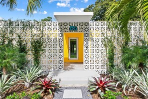A building with a white lattice facade, a yellow door, and a blue sign with the number 409. - Palm Springer - Heated Salt Water Pool (Wilton Manors)