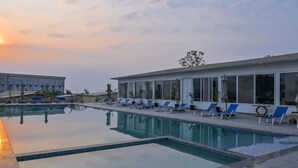 A swimming pool with lounge chairs and a building with large windows.