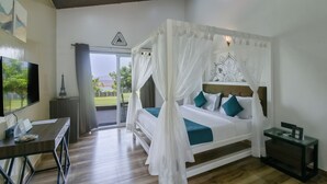 A bedroom with a four-poster bed, a television, a desk, and a view of the outdoors.